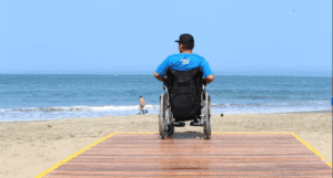 Foto de un usuario en silla de ruedas en la zona accesible en la playa a 20 metros de distancia de la orilla
