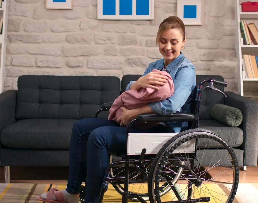 La madre en silla de ruedas sosteniendo una bebé.