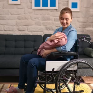 La madre en silla de ruedas sosteniendo una bebé.